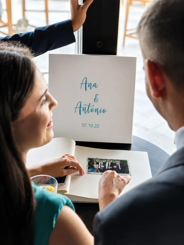 Una pareja mira su álbum de firmas personalizado con sus nombres y la fecha de la boda